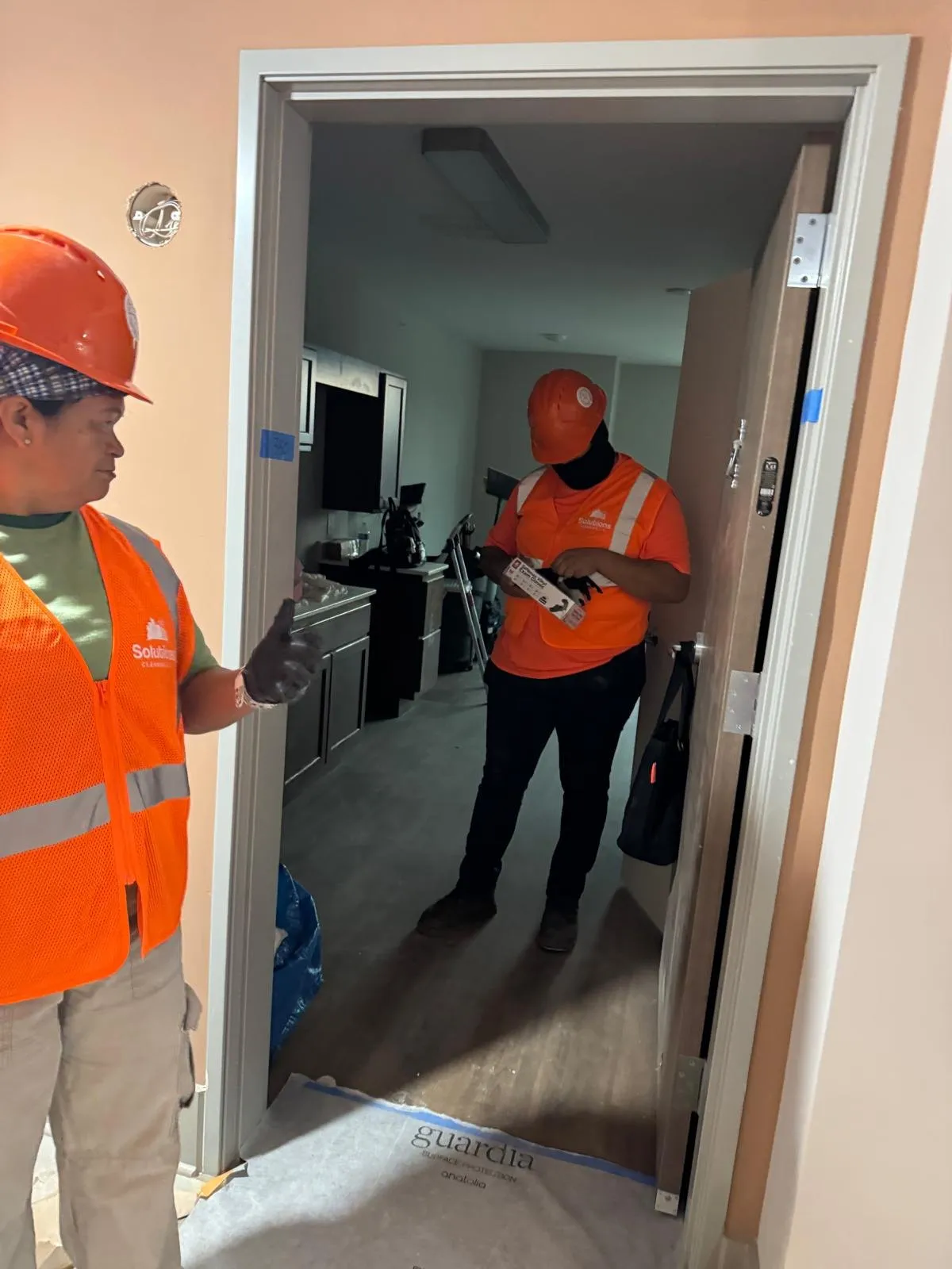 Solutions Cleaning team member in a hard hat preparing to clean a newly built apartment kitchen