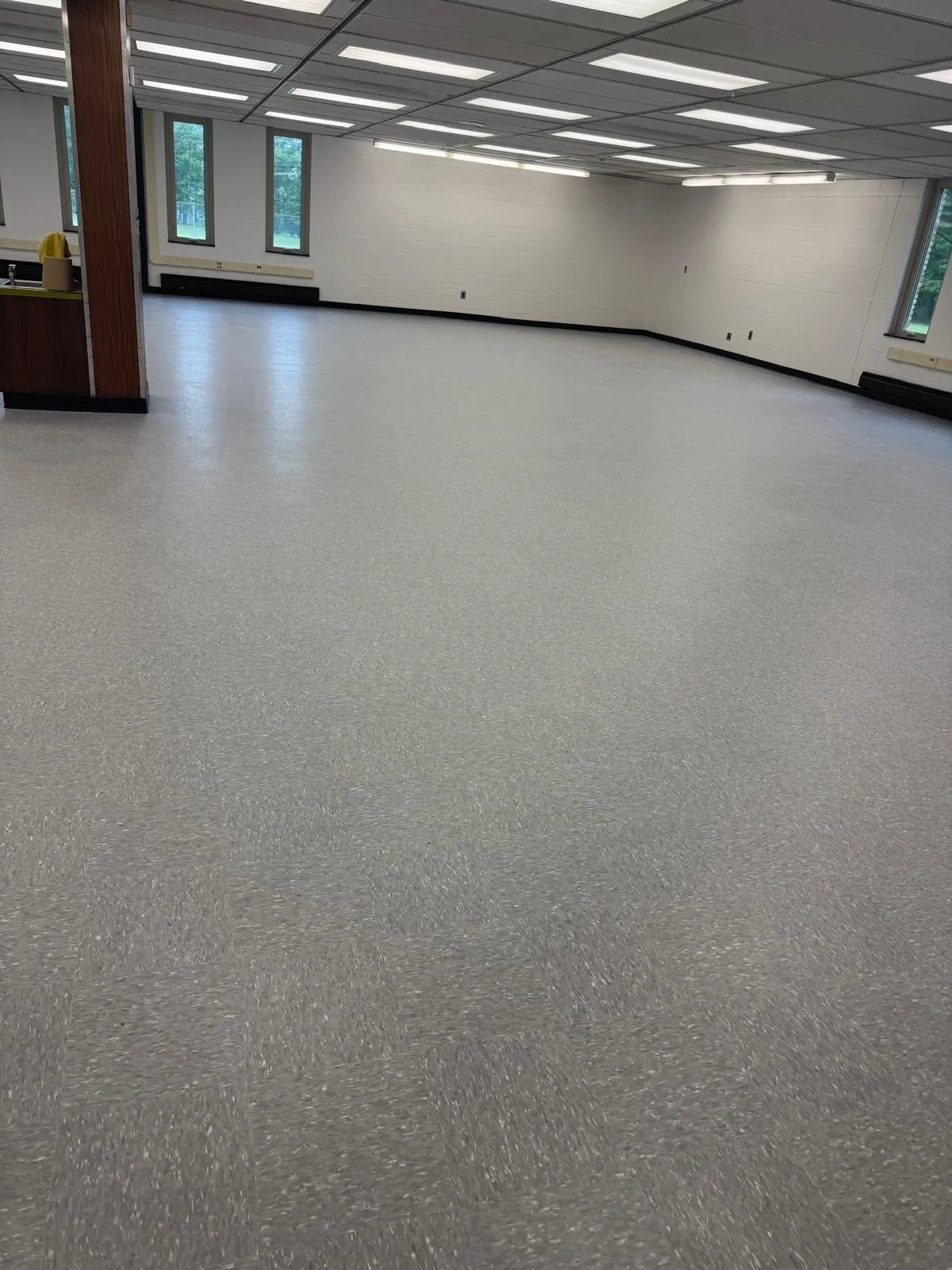 Large room with a dull, matte vinyl tile floor before strip and wax