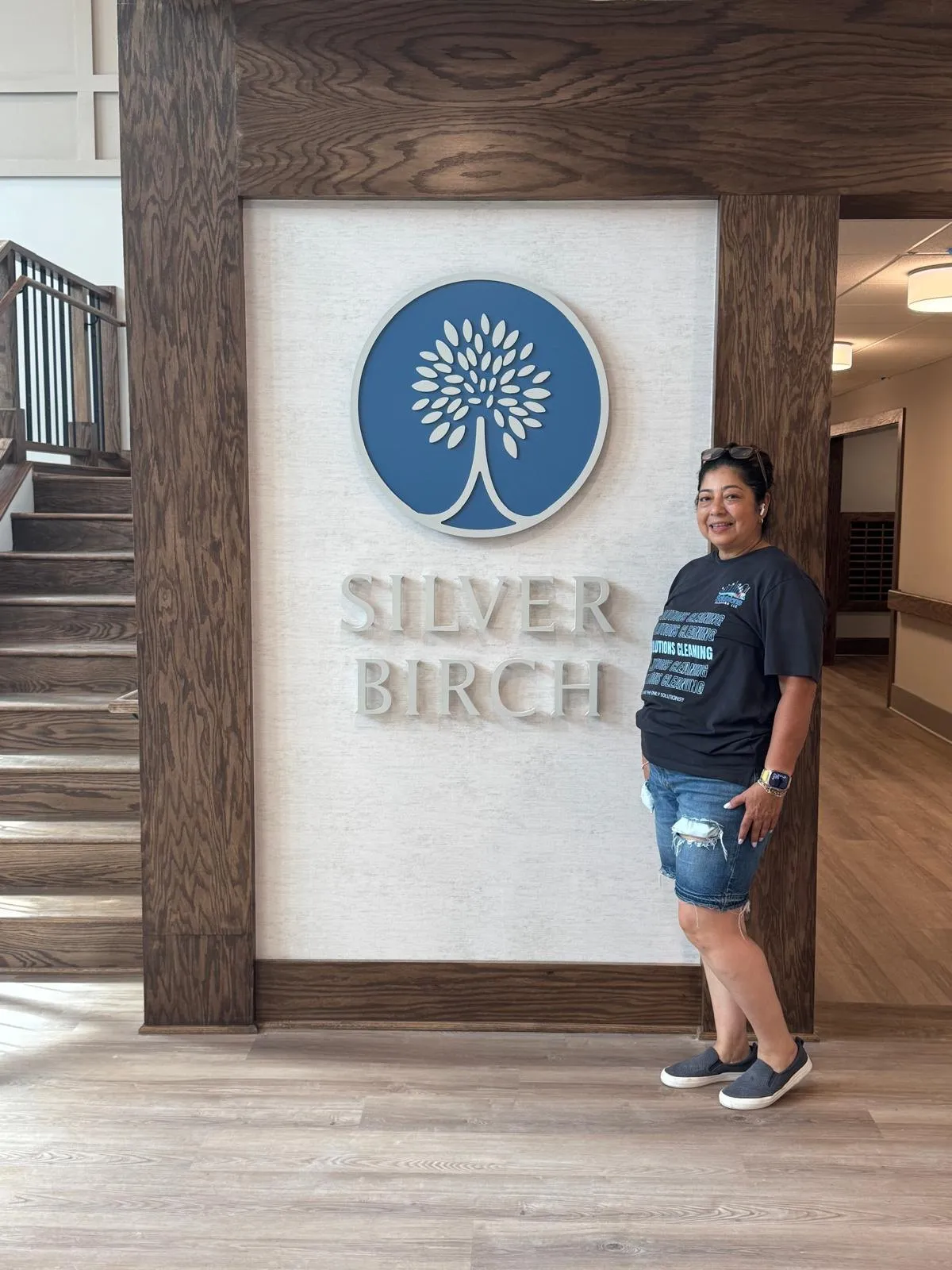 Solutions Cleaning team member beside the Silver Birch sign in the finished lobby