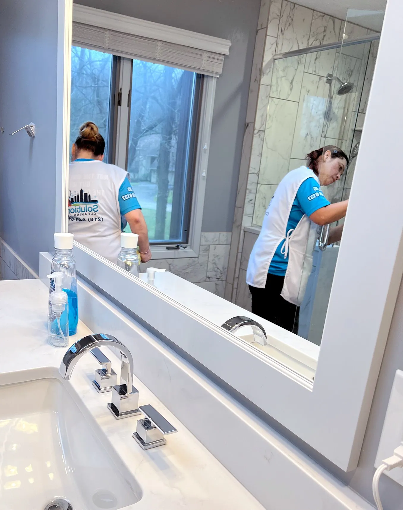 Solutions Cleaning team detailing a bathroom mirror and vanity