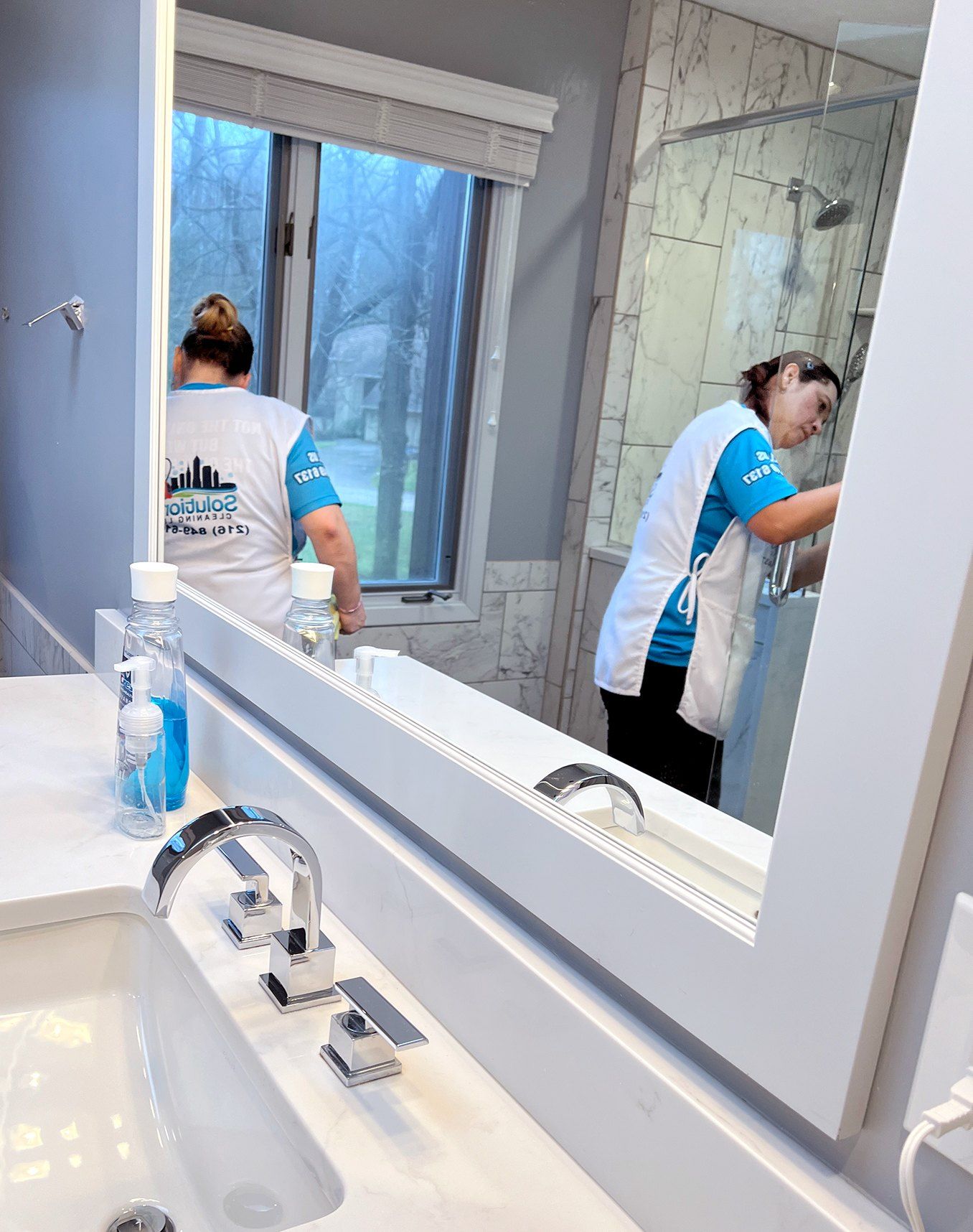 Solutions Cleaning team detailing a bathroom mirror and vanity