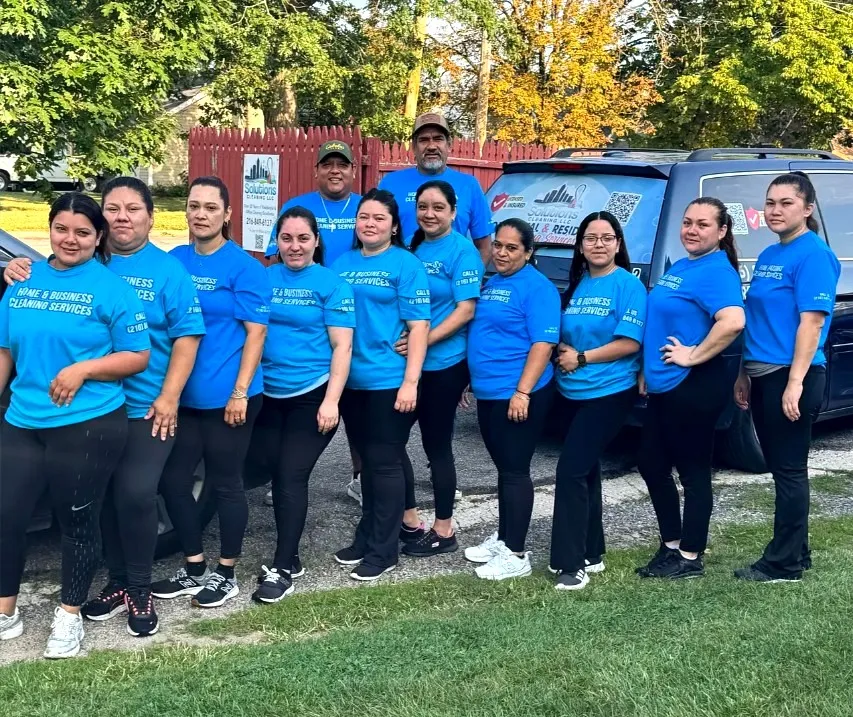 The Solutions Cleaning team in matching blue uniforms in front of the company van